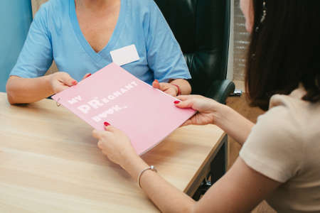 The gynecologist gives the girl a pregnancy diary. My pregnant book.の写真素材