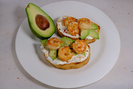 Avocado sandwiches, half of avocado, with seasame and shrimps on a white background on textured...