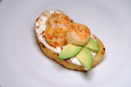 Avocado sandwiches, with seasame and shrimps on a white background on textured plate close up view macroの写真素材