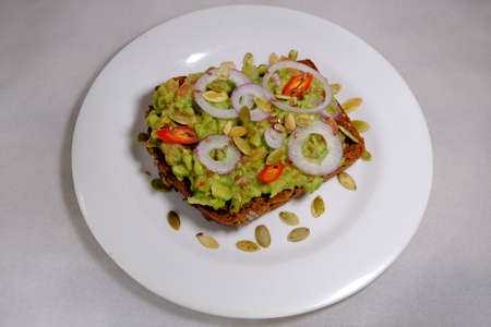 Avocado sandwiches, half of avocado, with peanuts and pumpkin seeds, onion rings, red pepper on a white background texturedの写真素材