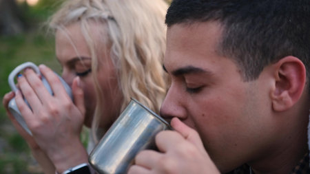 Young happy couple drinking tea, coffee while resting in autumn forest