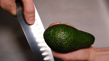 male hands cut avocado in half. Fresh ripe avocado, Healthy breakfast, Vegetarian foodの写真素材