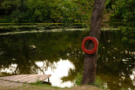 Lifebuoy ring on berth of the river with wooden pier outdoors.の写真素材