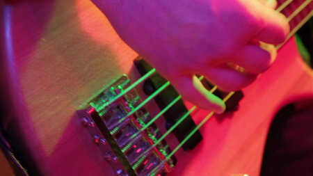 Hands of rock musician playing the electric bass guitar on repetitin in red light.の写真素材