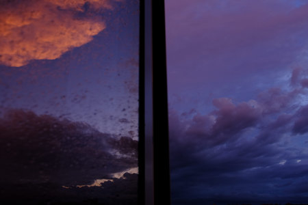 Dawn sky with colorfull clouds. Sunset landscape through the window with reflection on it