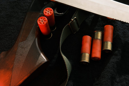 Weapon on black cloth: knife, rifle, shells,top view. Top view of knife, rifle shells