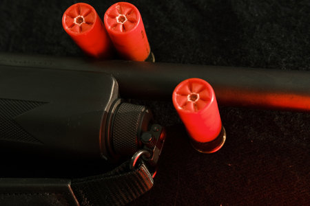 shell magazine into the barrel of a long shotgun on dark background with leather belt.の写真素材