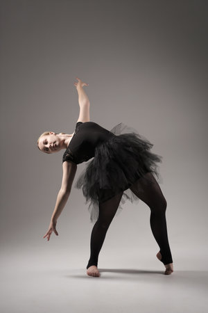 Ballerina Dancing with tutu Modern Ballet Dancer in dancer tutu, Gray Background. Dancer in Black clothes showing her flexibility posing on gray background in studioの写真素材