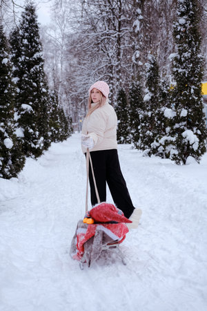 Mother or girl or woman walking in the forest in winter with sledges and white winter landscape on...