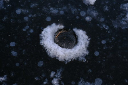 Winter fishing hole in the ice is frozen due to low temterature.の写真素材