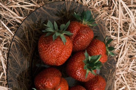 a lot of ripe juicy strawberries lying in a plate on a hay background view from above, diet , healthy productの写真素材