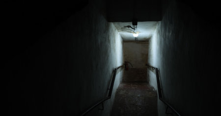 Dark old staircase in a bomb shelter with worn steps and dim lighting creates mysterious and eerie atmosphere ideal for historical abandoned, or post apocalyptic scenes or urban exploration conceptsの写真素材