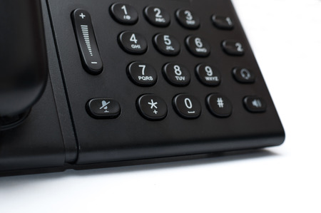 Black desk phone on the white background