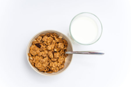 Brown cereals in the bowl and glass of milk on the white background