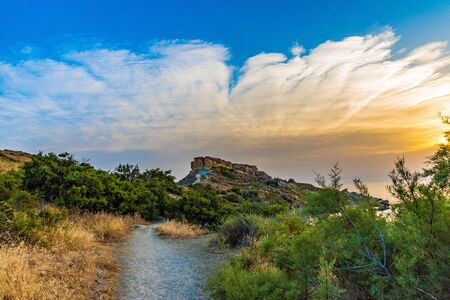 Beautiful sunset on the border of the sea with yellow rocks on the background of a blue skyの写真素材