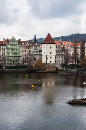 White ancient tower in Prague with colored buildings on teh backgroundの写真素材