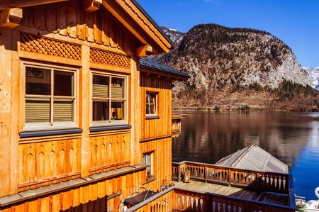 Yellow wooden house standing in front of the mountain next to clean lakeの写真素材