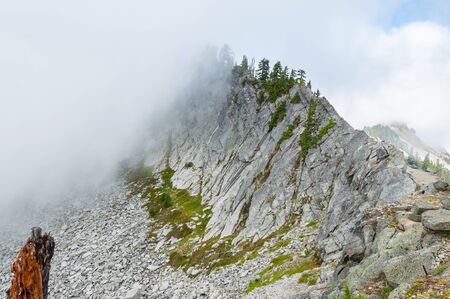 Rocky mountain peak covered with cloudの写真素材