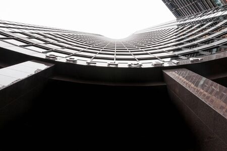 Bottom view of a skyscraper with a white sky on the backgroundの写真素材