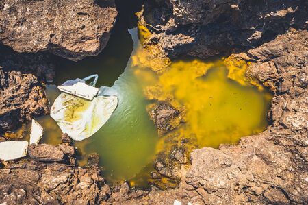 Polluted yellow water with a plastic bag in it on the European sea coastの写真素材