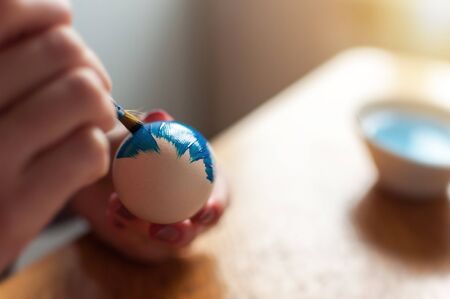 Close shot of hands painting egg in blueの写真素材