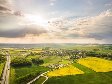 Drone shot of the highway and green and yellow rapeseed fields on a sunny weatherの写真素材