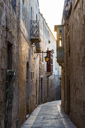 Yellow sun rays in the narrow street of an old cityの写真素材