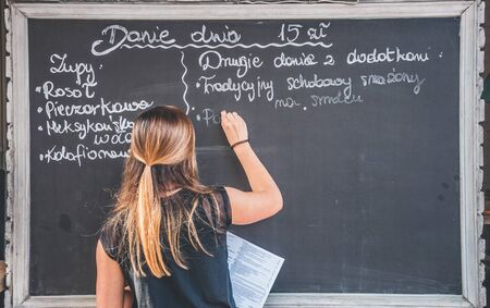 Young lady writing menu items on the black boardの写真素材