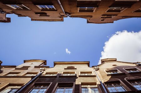 Spectacular view on the sky from the narrow street between the buildingsの写真素材