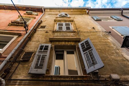 White shutters opened on the first floor of an ancient buildingの写真素材