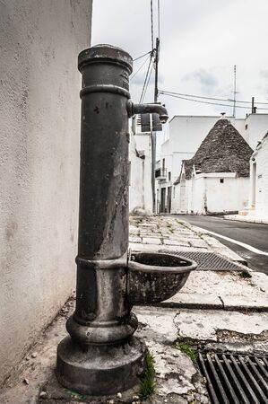 Old abandoned water pump on the sidewalkの写真素材