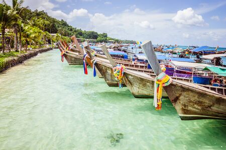 Traditional Thai wooden boats near sunny Thai beach on the Phi Phi islandの写真素材