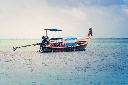 Traditional wooden thai boat in the middle of the ocean with cloudy sky on the backgroundの写真素材