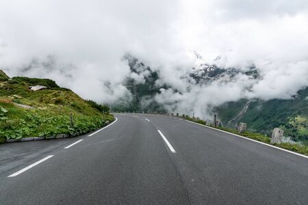 Deep white clouds covering the green mountains and a roadの写真素材