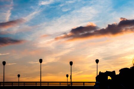 Dark silhouettes of peopl that are trying to make a photo of sunset with their smartphonesの写真素材
