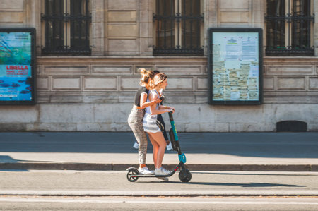 Paris, France - Apr 20, 2019 - Young girls riding an electric scooter in the middle of the road