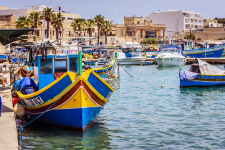 Marsaxlokk, Malta - June 22, 2019 - Small boat with yellow and blue stripes after fishing waiting to be unloadedのeditorial素材
