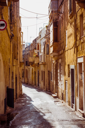 Mdina, Malta - June 22, 2019 - Old buildings on both sides of narrow street on Malta in the rays on sunsetのeditorial素材
