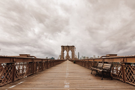Early morning on the Brooklyn Bridge under dark cloudsの写真素材