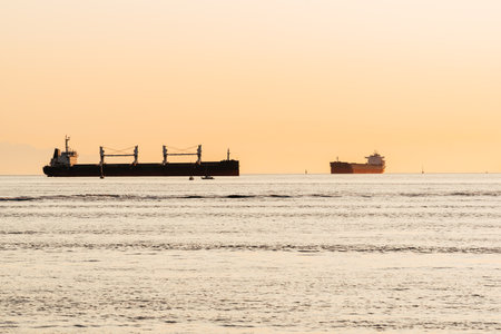 Ocean sunset lighting big cargo ships in Vancouver bayの写真素材