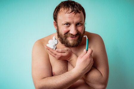 Happy bearded guy is ready to shave his beard. Man shaving.