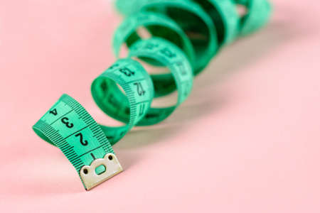 Measure Tape. Body measuring curly ruler sewing cloth Tailor soft tape on pink rose background.の写真素材