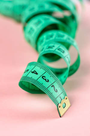 Measure Tape. Body measuring curly ruler sewing cloth Tailor soft tape on pink rose background.の写真素材