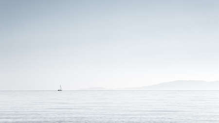 Minimalism, picture of small boat at the horizon,clear sky on Aegean sea, Halkidiki, Greece.の写真素材
