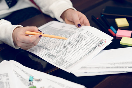 Woman fills the tax form, working with tax documents. Form 1040 Individual Income Tax return form....