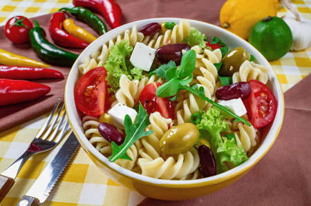 Pasta salad with tomato,arugula, cucumber, peppers,hot peppers, black and green olives, and cheese feta. Top view.の写真素材