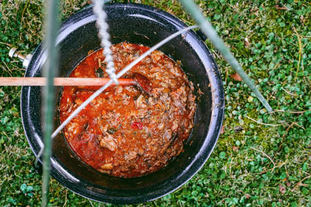 Cooking beef goulash soup in a cauldron. Cooking lunch in a natural environment in a pot on an open fire.の写真素材