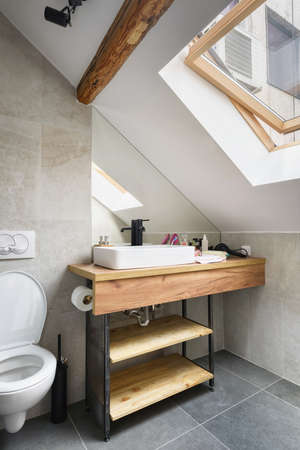 Attic apartment, modern bathroom, apartment interior design with old rustic wooden beams and furniture, stylish Italian granite ceramica.の写真素材