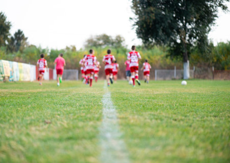 Young football players run in red and white shirts
