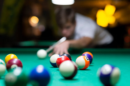 Handsome young man playing pool in pub